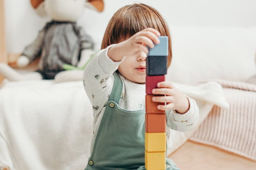 Bild på ett barn som bygger med byggstenar som symboliserar en stabil grund för framgångsrikt lärande.